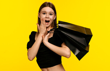 Excited Woman Holding Shopping Bags Against Yellow Background
