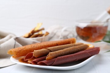 Tasty fruit leather rolls on white table, closeup. Space for text
