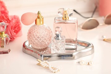 Bottles of different perfumes, accessories and flowers on dressing table indoors, closeup