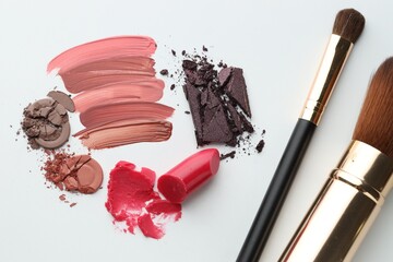 Different cosmetic products and makeup brushes on white background, flat lay
