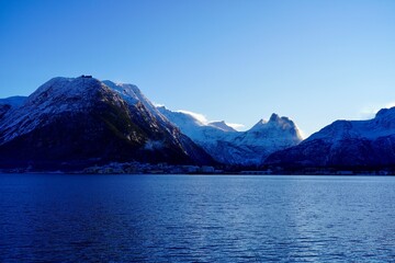Snow covered mountains rise sharply from the shores of the Isfjorden near the town of Aandalsnes,...
