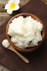 Natural shea butter and plumeria flower on wooden table, flat lay