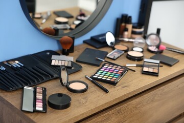 Different makeup products and brushes on vanity indoors, closeup