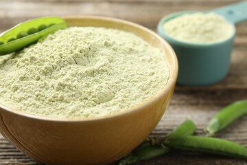 Protein powder and fresh pea pods on wooden table, closeup