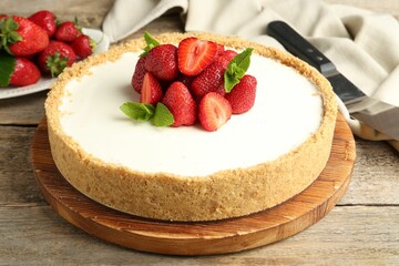 Tasty cheesecake with strawberries and mint on wooden table, closeup
