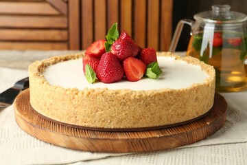 Tasty cheesecake with strawberries and mint on table against wooden background, closeup