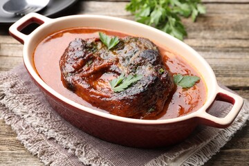 Traditional ossobuco dish with beef steak and sauce on wooden table, closeup