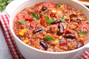 Tasty chili con carne in bowl on grey table, closeup