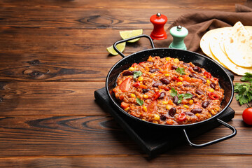 Tasty chili con carne in baking dish and flatbread on wooden table, closeup. Space for text