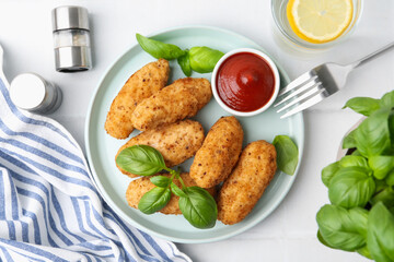 Tasty fried croquettes, basil and sauce served on white tiled table, flat lay