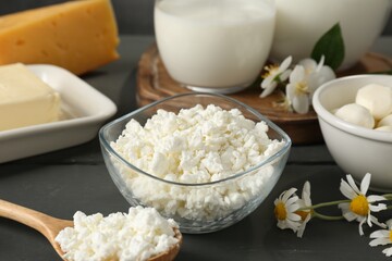 Fresh dairy products and flowers on grey wooden table, closeup