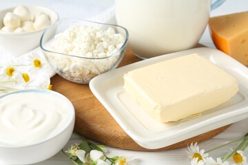 Fresh dairy products and flowers on white wooden table, closeup