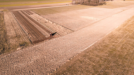 Dusty tractor working on agricultural land