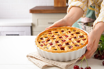 Woman with tasty cherry pie at white wooden table, closeup. Space for text