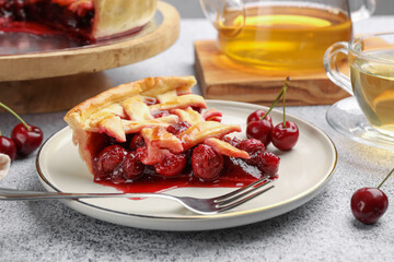 Piece of tasty cherry pie, berries and fork on grey textured table, closeup