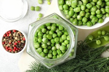 Fresh green peas, pickling jar, spices, salt and dill on white table, flat lay