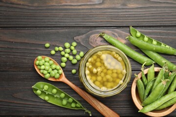 Pickled peas in jar and pods on black wooden table, flat lay
