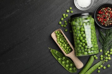 Fresh green peas in pickling jar, pods, spices and salt on black table, flat lay. Space for text