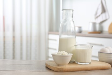 Different dairy products and eggs on wooden table in kitchen, space for text