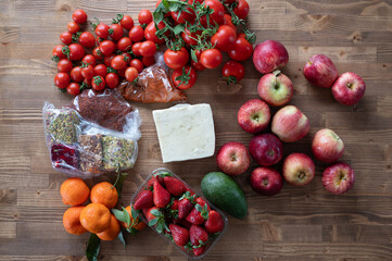 Variety of fresh fruits and vegetables, including tomatoes, apples, and strawberries, arranged on a wooden table, showcasing healthy eating options