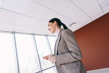 Successful businesswoman standing in the office interior, highlighting corporate style and...