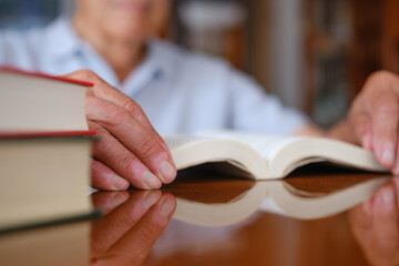 Elderly man reading a book with focus on hands and reflection