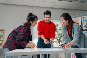 Three asian ui/ux designers are working on a new mobile application interface, comparing mockups...