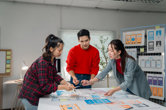 Creative team engaging in a brainstorming session for a mobile application design. Diverse group discussing layout and user interface, surrounded by wireframes and design tools - Powered by Adobe