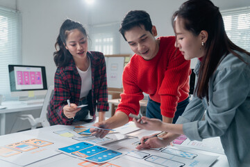 Three asian ux designers working together on developing an app interface wireframe for a mobile...
