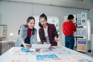 Creative team working on a mobile app design, discussing layout and user interface. Two women focus...