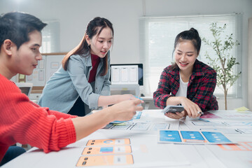 Young asian ux ui designers working on mobile app interface wireframe design at modern bright...