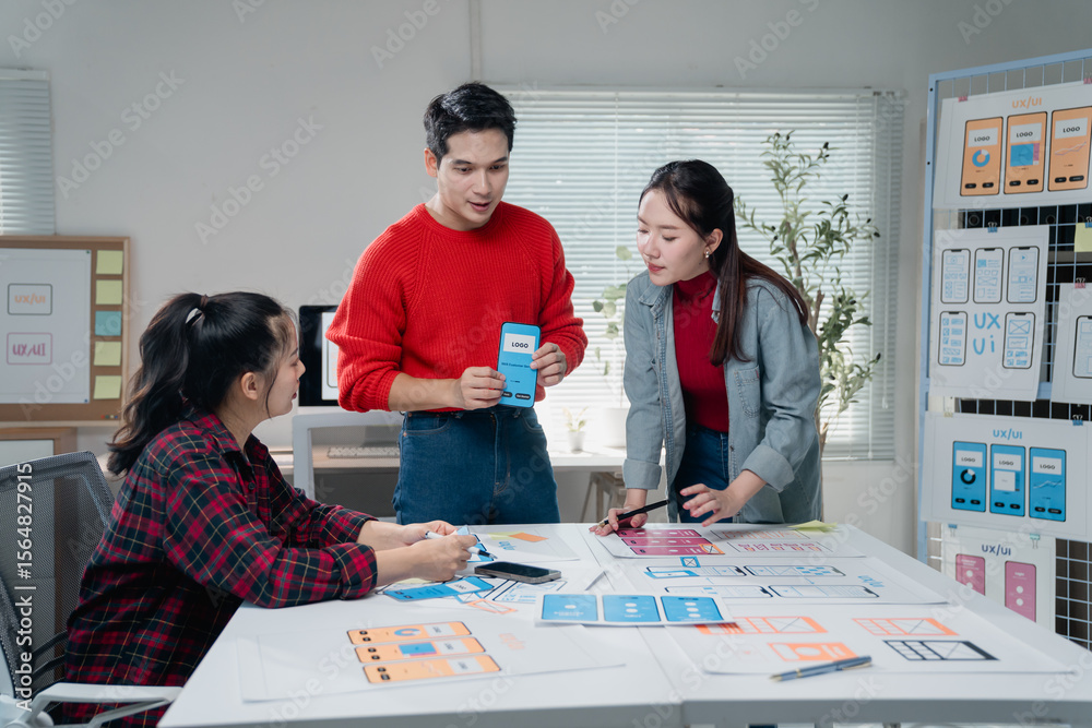 Poster creative team engaged in developing a mobile app interface, discussing design elements and user expe