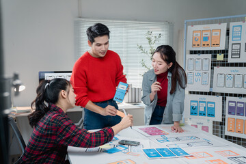 Diverse team of designers actively collaborates on a mobile app project, discussing user interface layouts and wireframes. They are focused on creating an intuitive and user-friendly experience