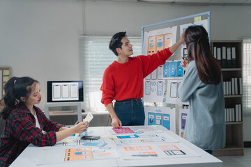 Group of young professionals engaged in a brainstorming session for a mobile app design. They are...
