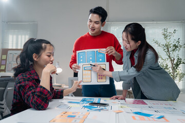 Creative team discussing and brainstorming mobile app design in a modern office. Colleagues...