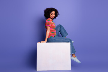 Charming young woman in casual style outfit posing against a violet background, exuding happiness,...