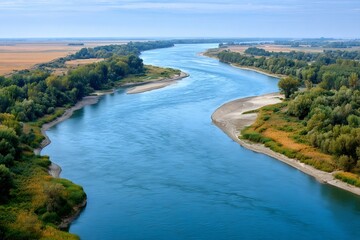 Obraz premium Vistula river flowing through green fields under blue sky in poland