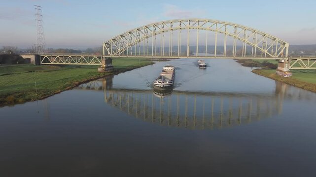 A cargo ship sailing on the river the Rhine and passing under the Oosterbeek railway bridge