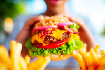 Close up of person enjoying big bite of cheeseburger with fries and toppings