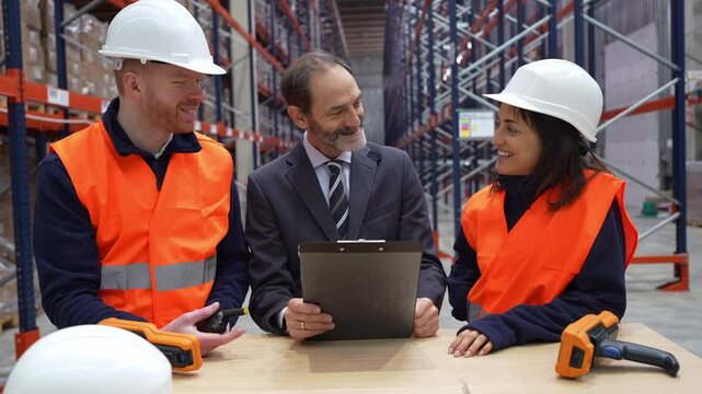 Professional warehouse team reviewing inventory logistics with clipboard, collaborating on strategic operational management in well organized storage facility