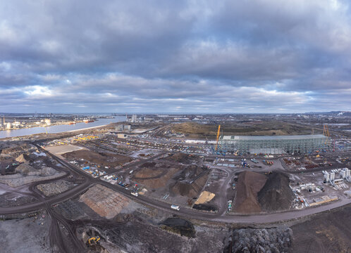 Aerial view of the industrial landscape with earth tones meeting the steely river, under a vast, textured sky, Port of Middlesbrough, England, United Kingdom.