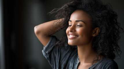 Fototapeta premium Joyful black woman playfully styling her hair in soft light.