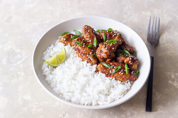 Chicken wings in teriyaki sauce with rice, sesame and onion. Asian food.