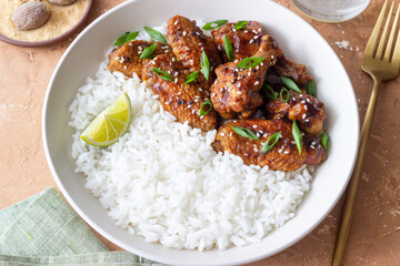 Chicken wings in teriyaki sauce with rice, sesame and onion. Asian food.