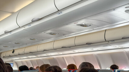 Rows of travelers nestled under aircraft overhead bins evoke wanderlusts whisper, hinting at World...