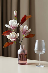 Pink vase holds magnolia blossoms, elegant display.
