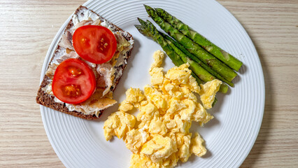 Savory scrambled eggs and vibrant asparagus dance beside rye toast under tomato crescents, perfect for Ostara feasts and hygge mornings