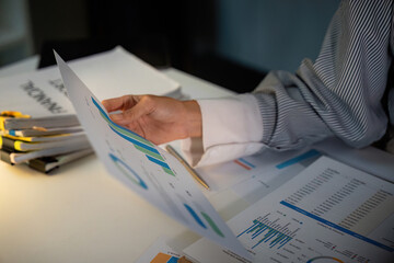 Late Night Analysis. Professional reviewing financial graphs and reports.