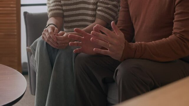 Cropped slowmo shot of hands of unrecognizable husband gesticulating while sharing emotions during couples therapy session with loving wife comforting him and giving emotional support