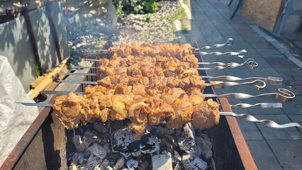 Juicy Cuts of Meat Grilling Over Charcoal in a Backyard Barbecue Setting Near the House.